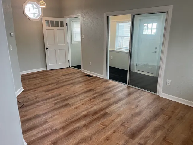 a view of empty room with window and wooden floor