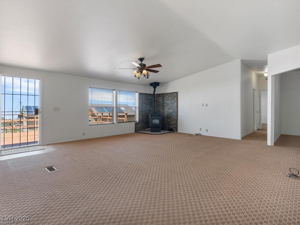 70 West Bonanza Road Las Vegas, NV 89124 - Photo 13 of 71 Unfurnished living room with a wood stove, light colored carpet, and ceiling fan