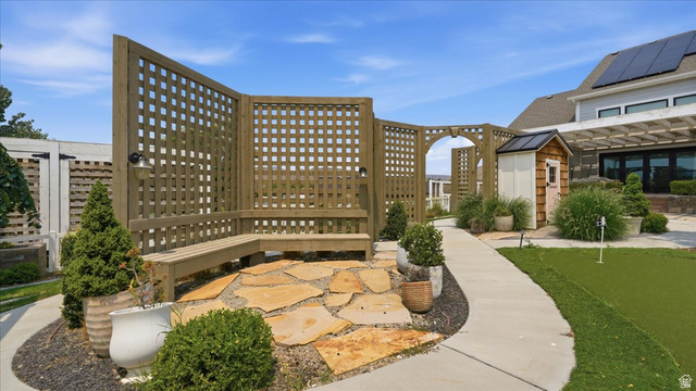 2038 East Ranch Road Eagle Mountain, UT 84005 - Photo 51 of 66 Curved lattice privacy screen with integrated bench seating, natural stone patio, and a dedicated putting green