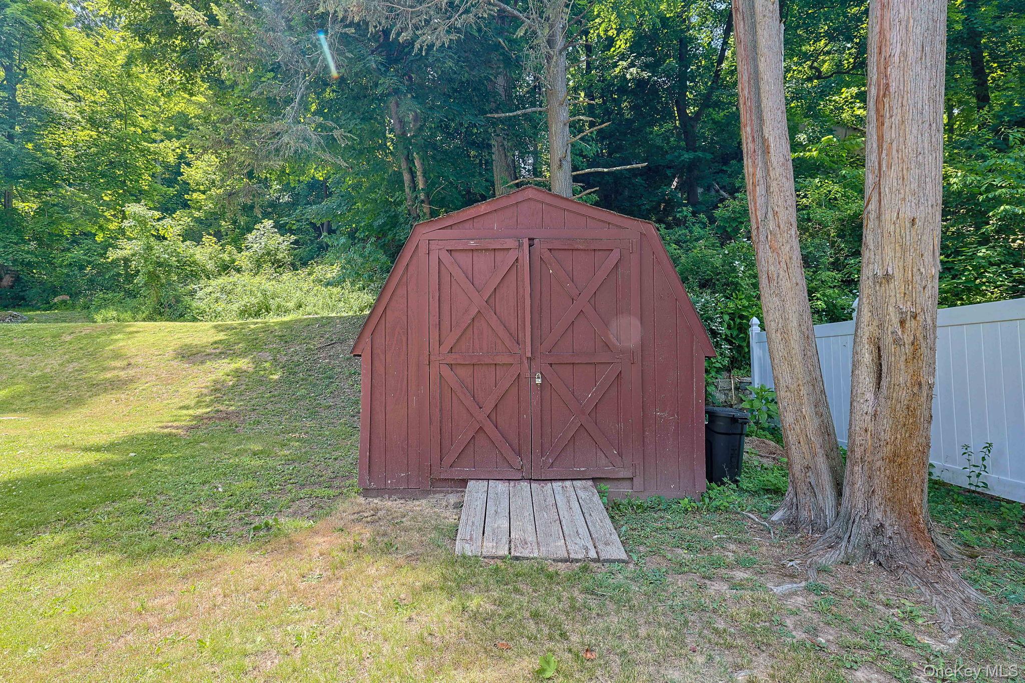 9 Library Road Tuxedo Park, NY 10987 - Photo 35 of 37 Red wood-sided shed with double barn doors, featuring a wood plank ramp entry