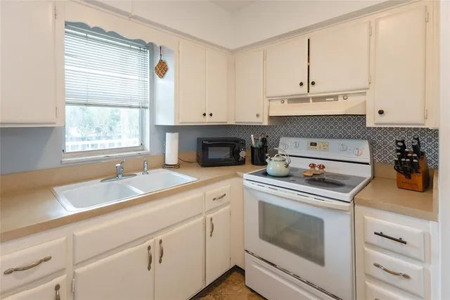 a kitchen with granite countertop white cabinets stainless steel appliances and a sink