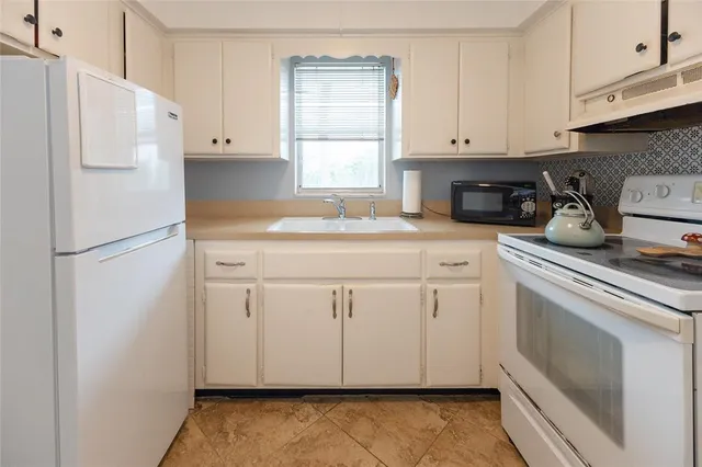 a kitchen with white cabinets and white appliances