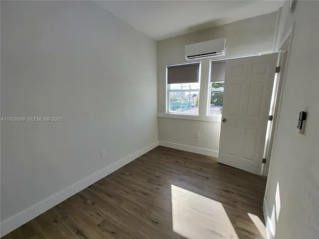 an empty room with wooden floor and window