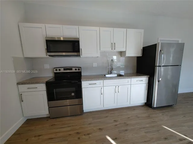 a kitchen with white cabinets and stainless steel appliances