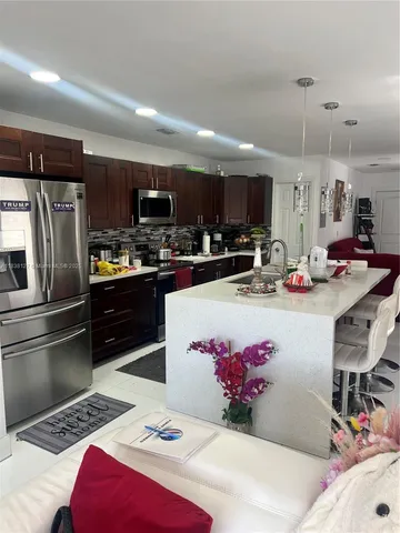 a kitchen with stainless steel appliances kitchen island granite countertop a sink refrigerator and microwave