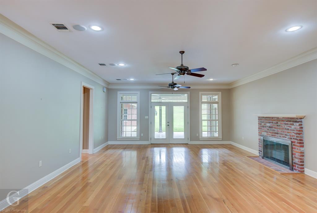 1212 WPA Road Homer, LA 71040 - Photo 9 of 35 Unfurnished living room with baseboards, a brick fireplace, crown molding, light wood-style floors, and ceiling fan