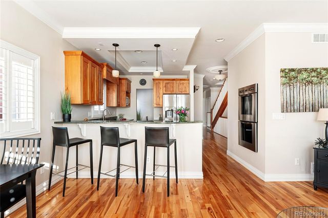 a living room with stainless steel appliances kitchen island granite countertop furniture and a wooden floor