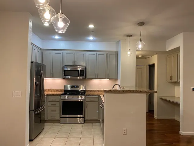 a kitchen with kitchen island granite countertop stainless steel appliances cabinets a sink and a counter top space