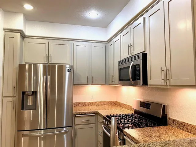 a kitchen with stainless steel appliances granite countertop a refrigerator and a stove top oven