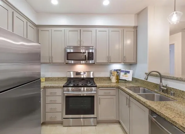 a kitchen with granite countertop a sink stove and microwave
