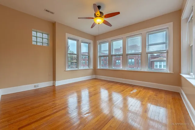 a view of an empty room with window and wooden floor