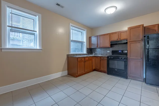 a kitchen with granite countertop a refrigerator and a stove top oven