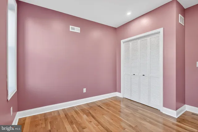 a view of an empty room with wooden floor and a fireplace
