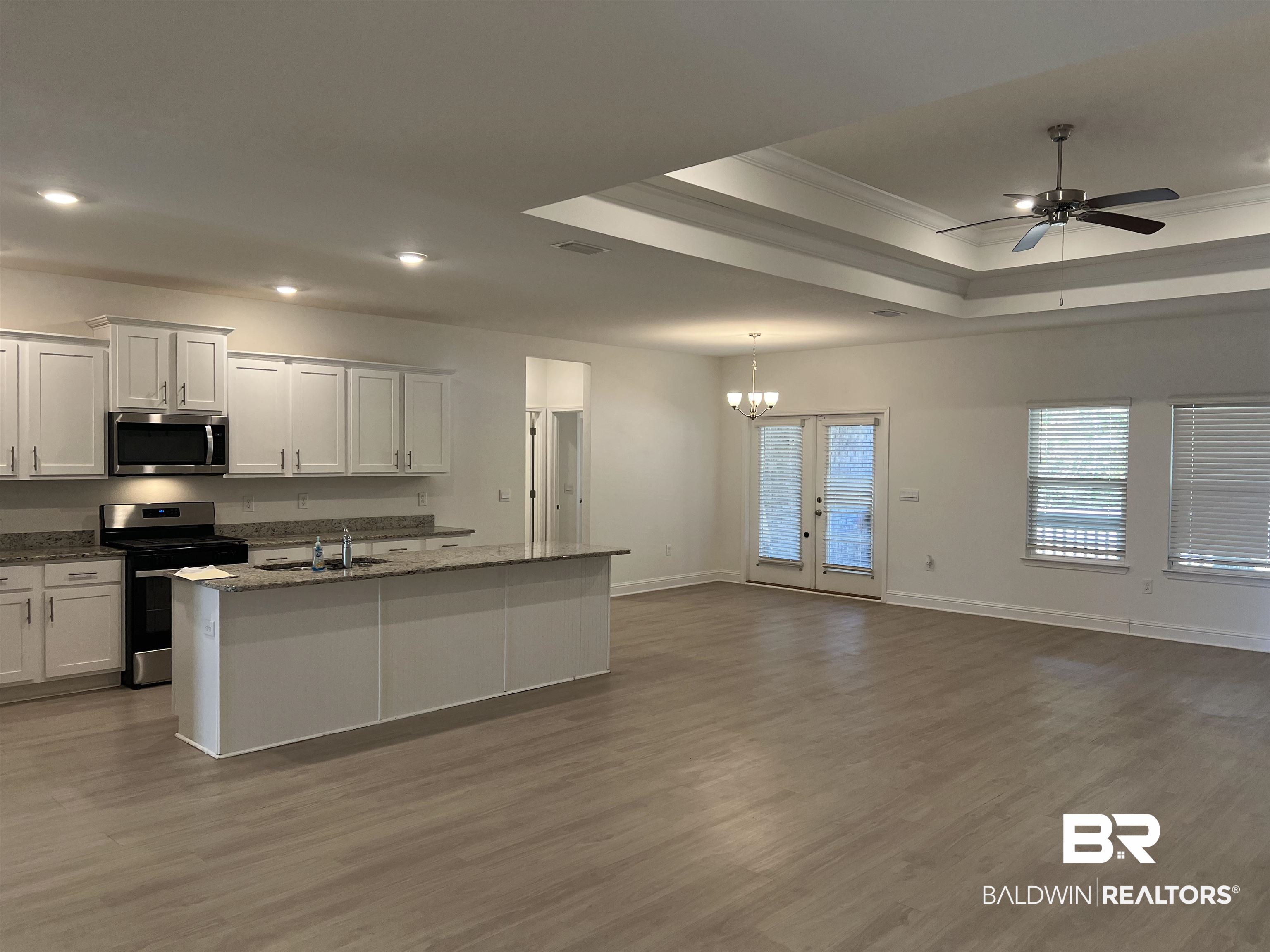 8855 Calverton Street Foley, AL 36535 - Photo 24 of 76 Kitchen with appliances with stainless steel finishes, ceiling fan with notable chandelier, wood-type flooring, a center island with sink, and white cabinets