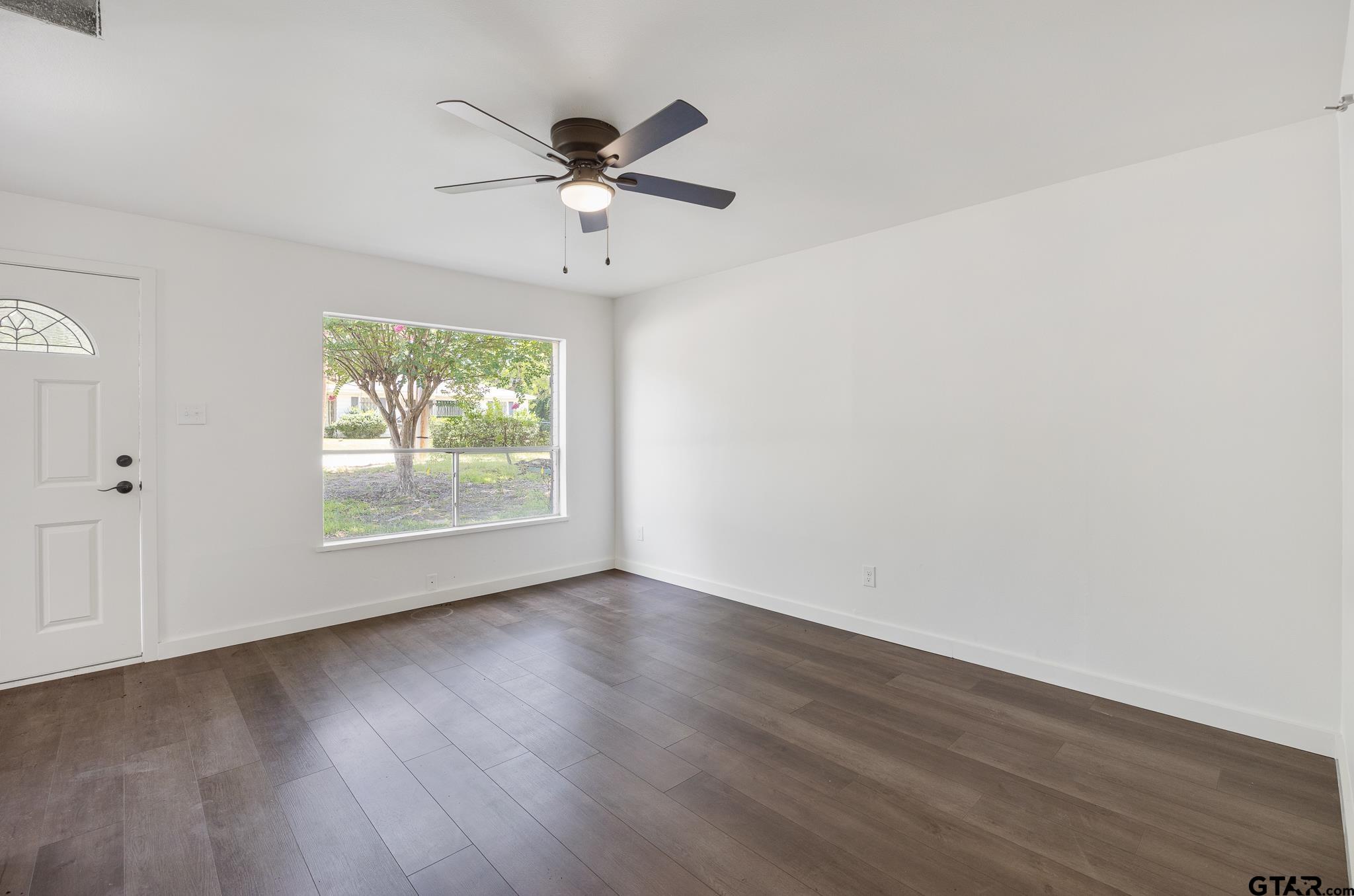 1538 North Hill Road Tyler, TX 75702 - Photo 6 of 29 an empty room with wooden floor chandelier fan and windows