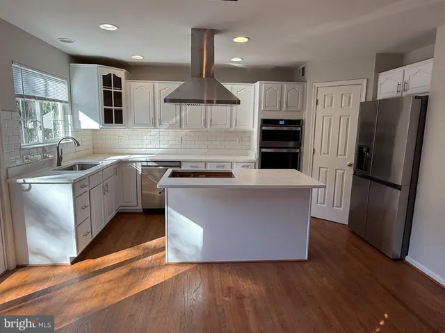 a large kitchen with stainless steel appliances granite countertop a stove a refrigerator a sink a microwave and wooden floor