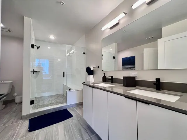 a bathroom with a granite countertop sink a toilet a mirror and shower