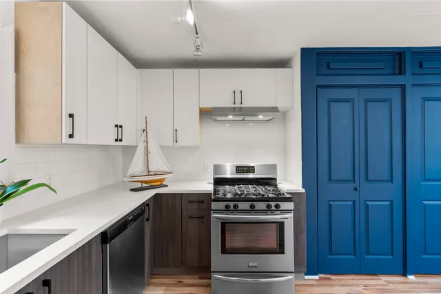 a kitchen with stainless steel appliances a stove and white cabinets
