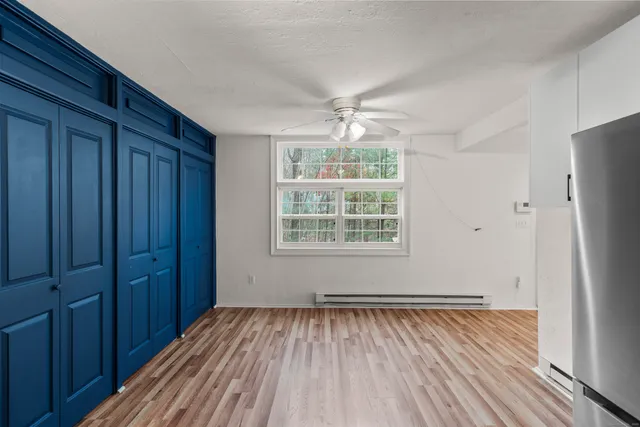 an empty room with wooden floor cabinet and windows