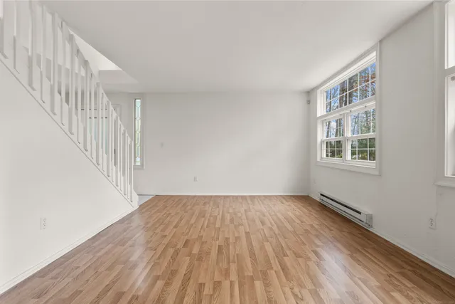 a view of an empty room with wooden floor and stairs