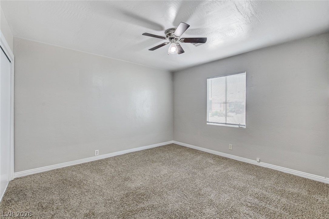214 West Victory Road Henderson, NV 89015 - Photo 17 of 33 A comfortable bedroom with soft carpeting and a ceiling fan, offering a tranquil retreat.