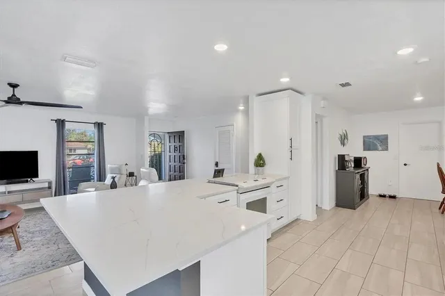 a large white kitchen with a refrigerator a stove a sink dishwasher and white cabinets with wooden floor