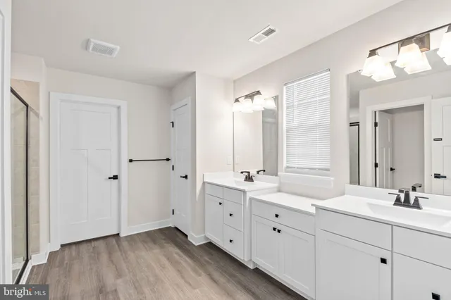 a spacious bathroom with double vanity a mirror and a shower
