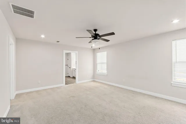 an empty room with windows and ceiling fan