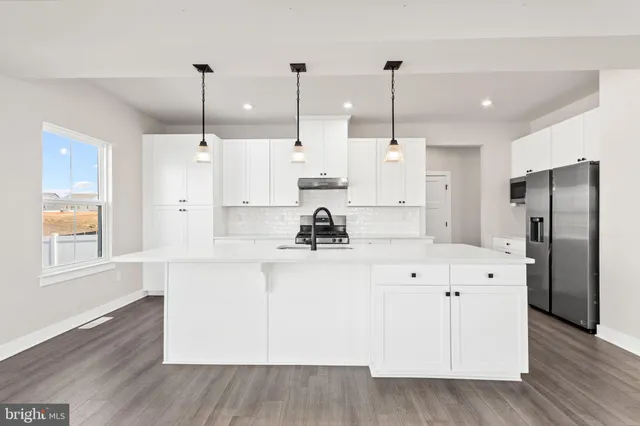 a view of a kitchen with kitchen island white cabinets and stainless steel appliances
