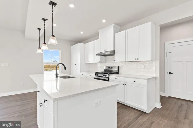 a kitchen with kitchen island granite countertop a sink a counter space appliances and cabinets