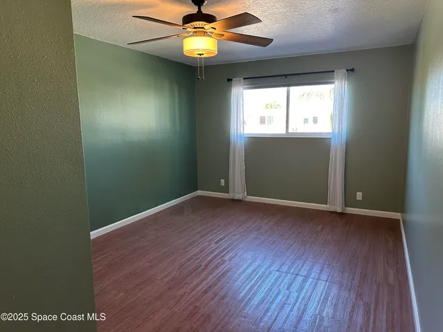 an empty room with wooden floor and chandelier