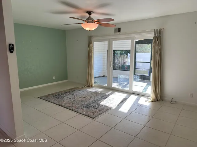 a view of an empty room with window and chandelier fan