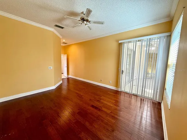 a view of empty room with wooden floor and fan