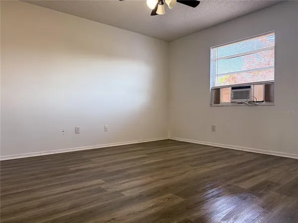 an empty room with wooden floor cabinet and mirror