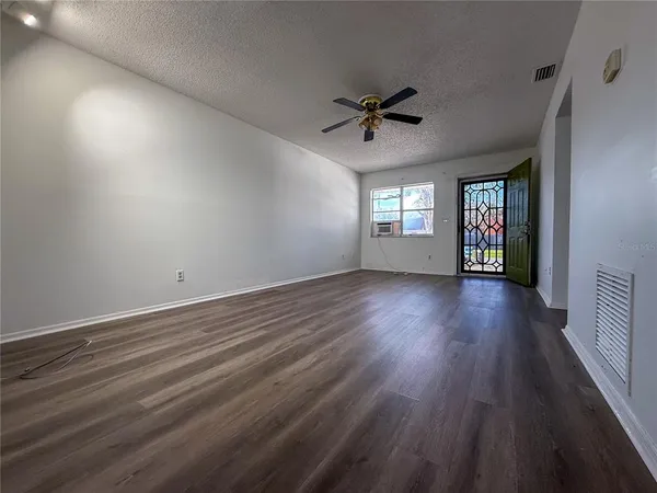 a view of an empty room with window and wooden floor