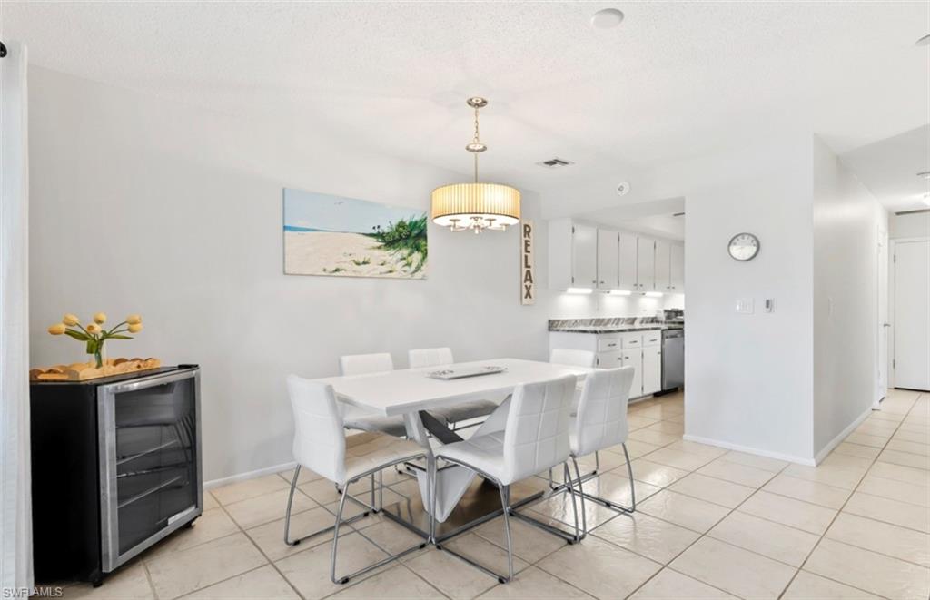 136 Harrison Road, Unit 1 Naples, FL 34112 - Photo 7 of 29 Open-concept dining area featuring tile flooring, a contemporary chandelier, and a pass-through opening to the kitchen