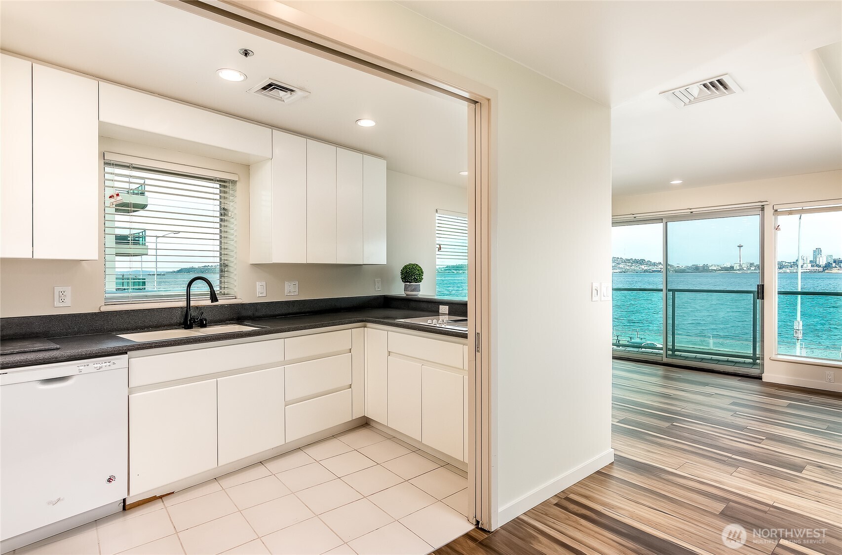 1027 Harbor Avenue Southwest, Unit 303 Seattle, WA 98116 - Photo 13 of 20 a kitchen with granite countertop a sink and white cabinets with wooden floor