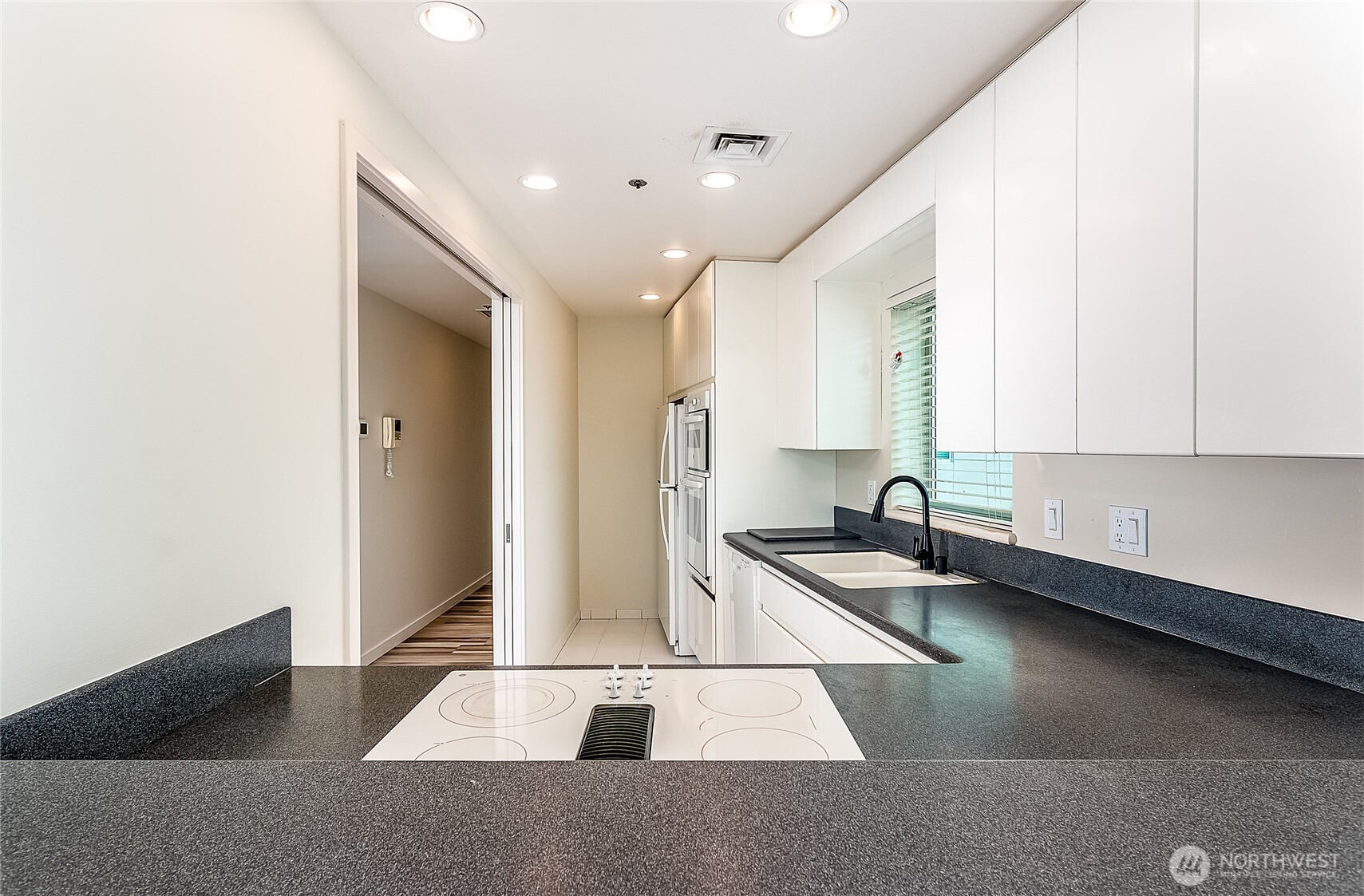 1027 Harbor Avenue Southwest, Unit 303 Seattle, WA 98116 - Photo 14 of 20 a kitchen with granite countertop a sink and white cabinets