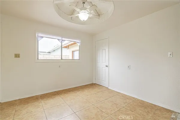 an empty room with a chandelier fan and windows