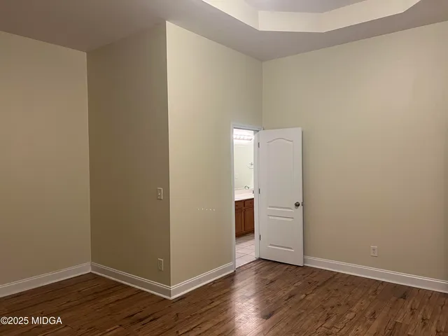 a view of an empty room with wooden floor and closet