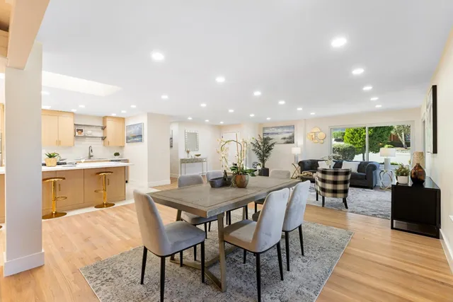 a dining hall with stainless steel appliances a dining table and chairs with kitchen view