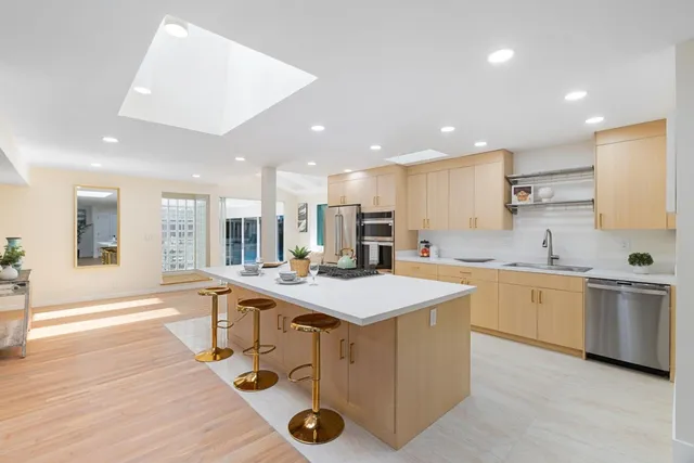 a large kitchen with kitchen island a sink a stove a dining table and chairs