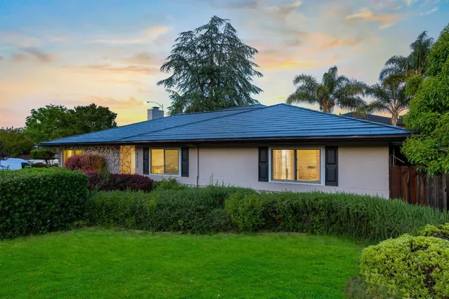 a front view of a house with a yard and potted plants
