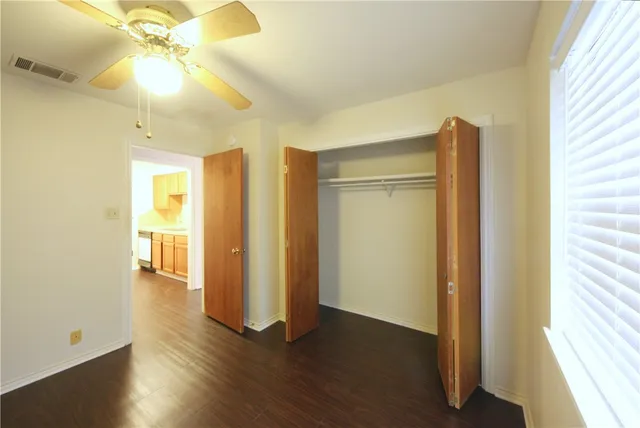 a view of an empty room with window wooden floor and a chandelier fan