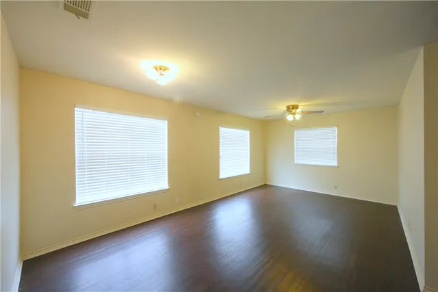 an empty room with wooden floor and windows