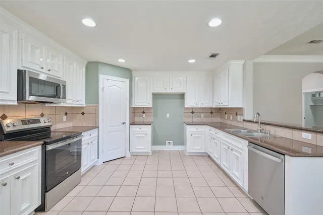 a large white kitchen with kitchen island a chandelier a large kitchen island white cabinetry and chandelier