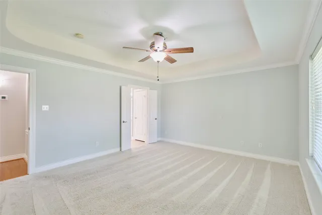 an empty room with chandelier fan and windows