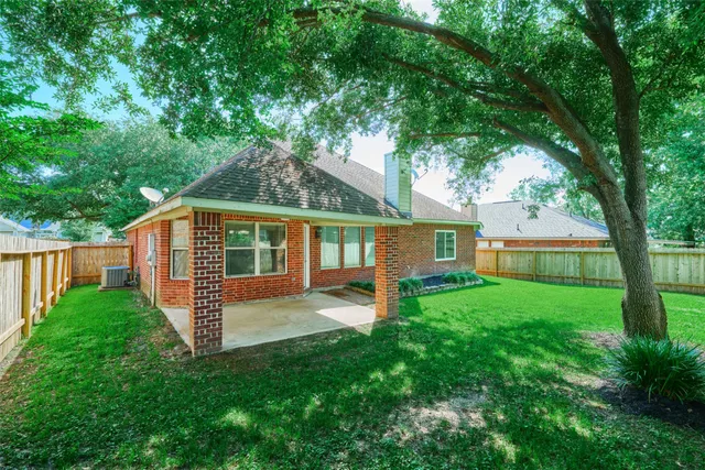 a view of a yard in front of a house with plants and large tree