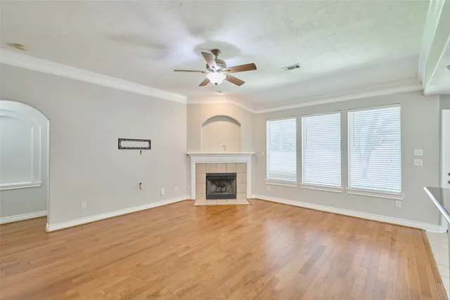 a view of an empty room with chandelier fan and wooden floor
