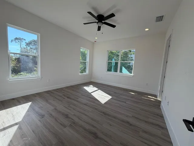 a view of empty room with wooden floor and fan